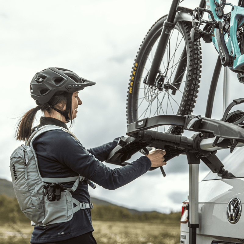 A woman is handling her bike on a Thule WanderWay 2bike Platform