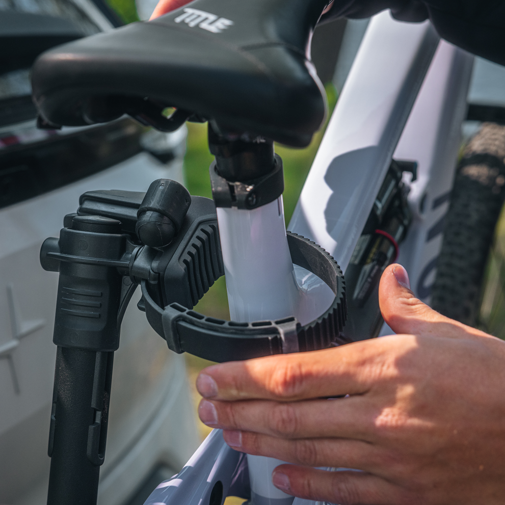 A man is using the Thule VeloLite individual bike arms with strap to secure a bike.