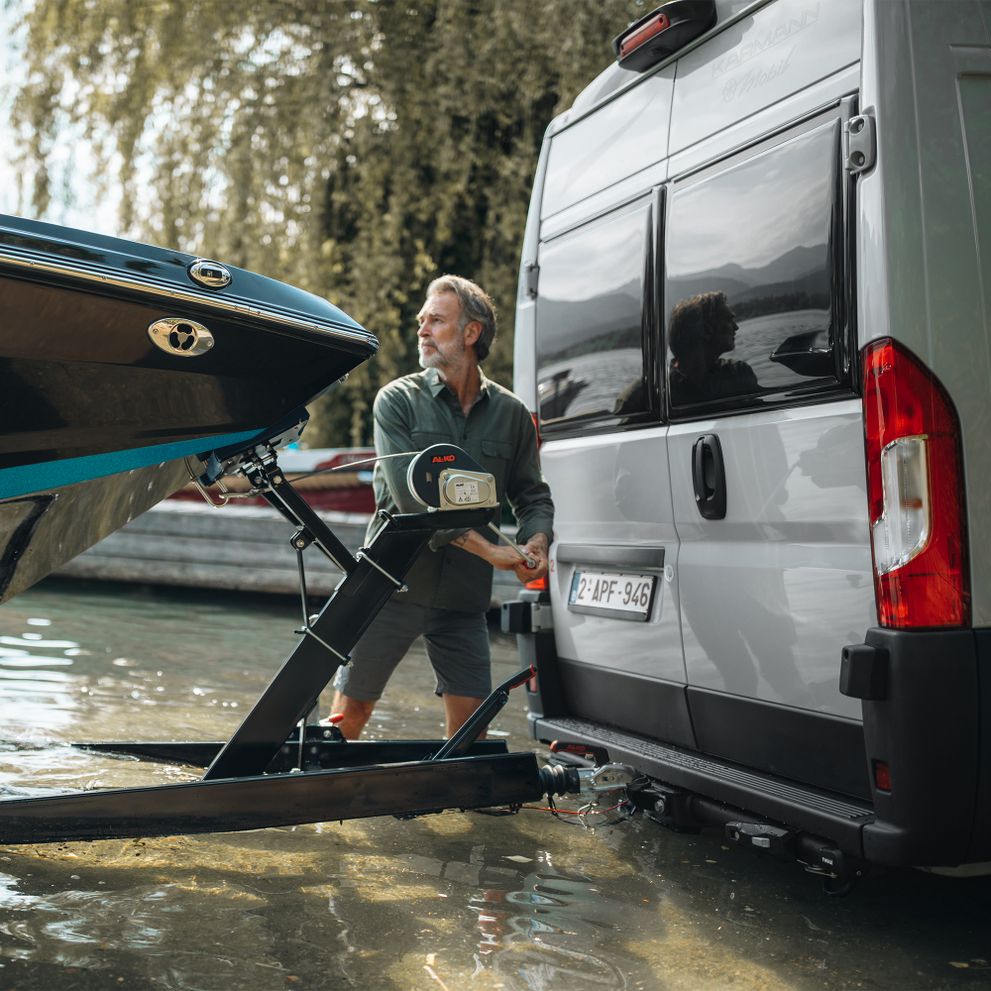 A man attaches his boat to the Thule VeloSwing van towbar installed on his white van.