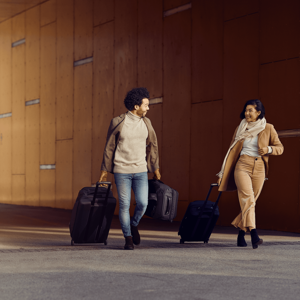 A man and woman walk with Thule Crossover 2 Wheeled Duffel suitcases through a tunnel.