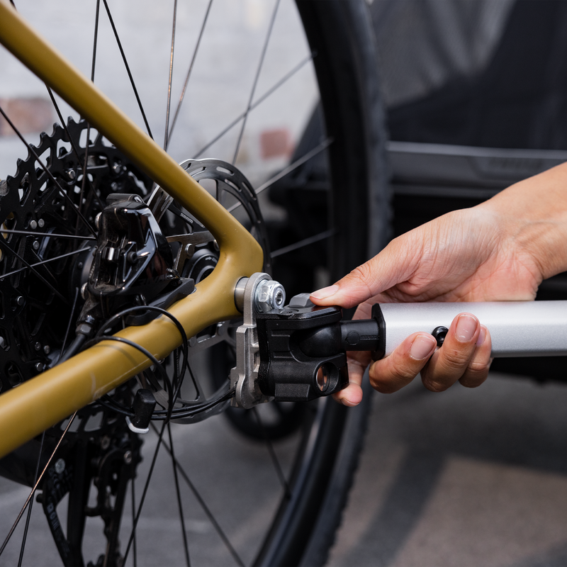 A close up of the Thule Chariot bike trailer being attached to the wheel of a bike.