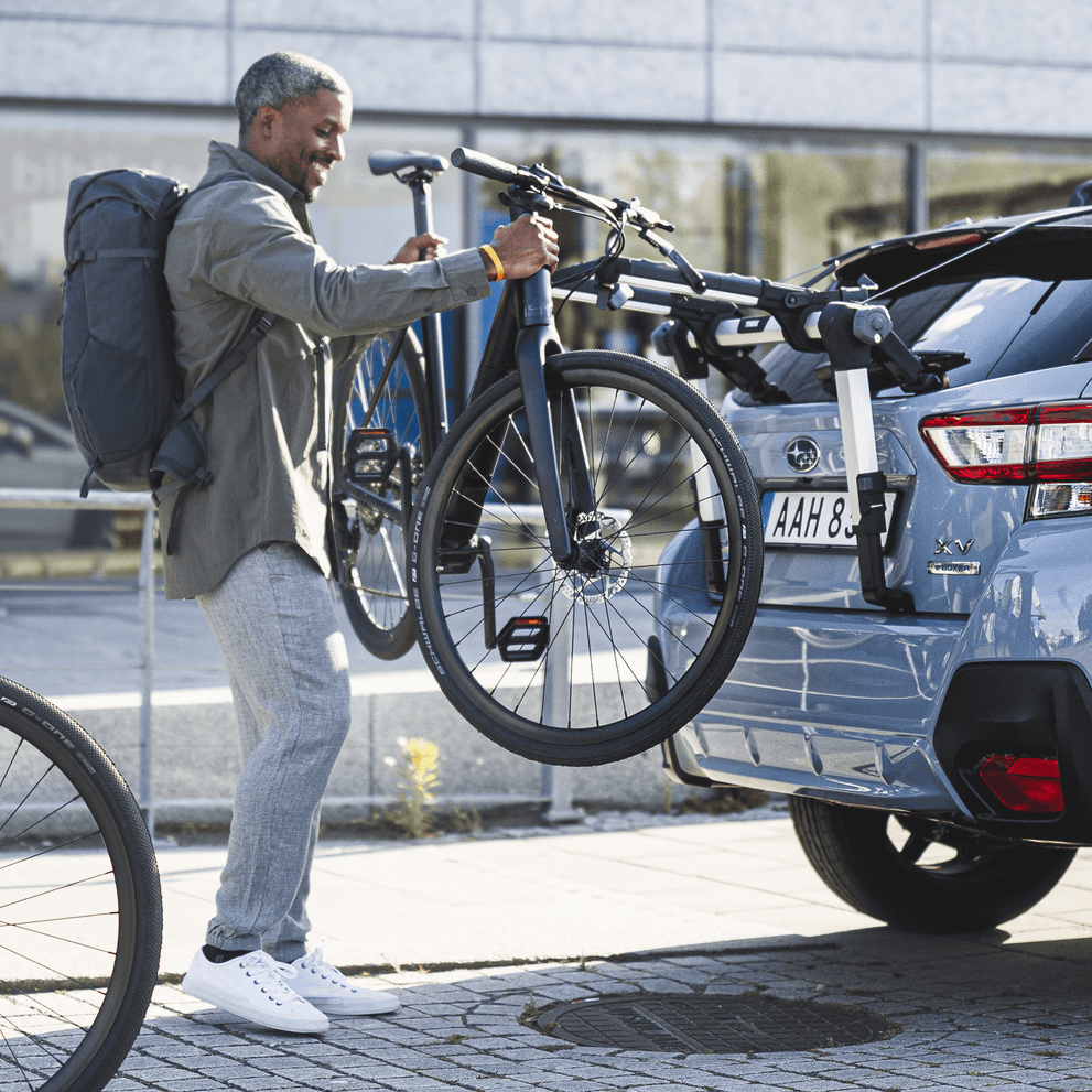 Close-up of a man instlaling bikes into a Thule OutWay Hanging trunk bike rack.