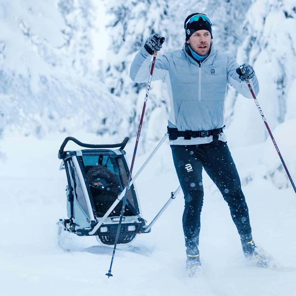 A man goes skiing with a Thule Chariot Cross and ski kit.
