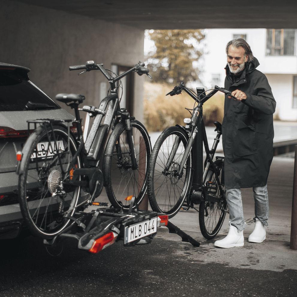 A man rolls his bike onto the Thule Epos hitch bike rack using the loading ramp accessory.