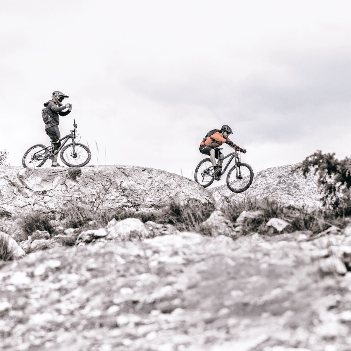 Two people go mountain biking in a rocky trail with a Thule Vital hydration backpack.