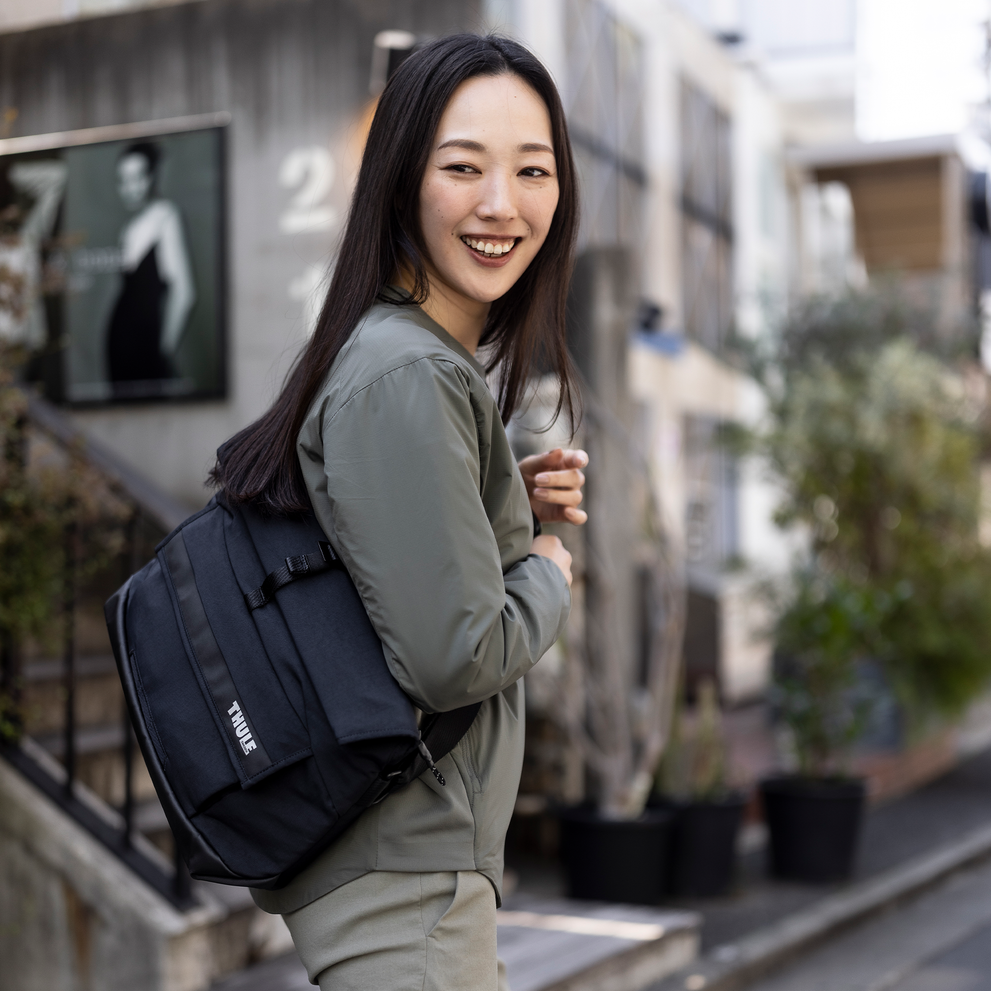 Woman walks down a street with a Thule Paramount 14L crossbody bag.