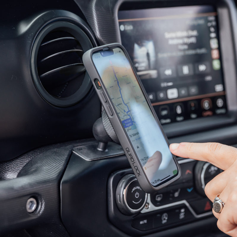Telefoon bevestigd op Quad Lock dashboardsteun in een auto.
