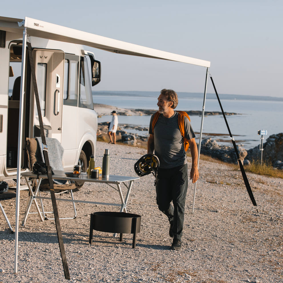 A person walks towards an RV with a Thule Hold Down Side Strap Kit.