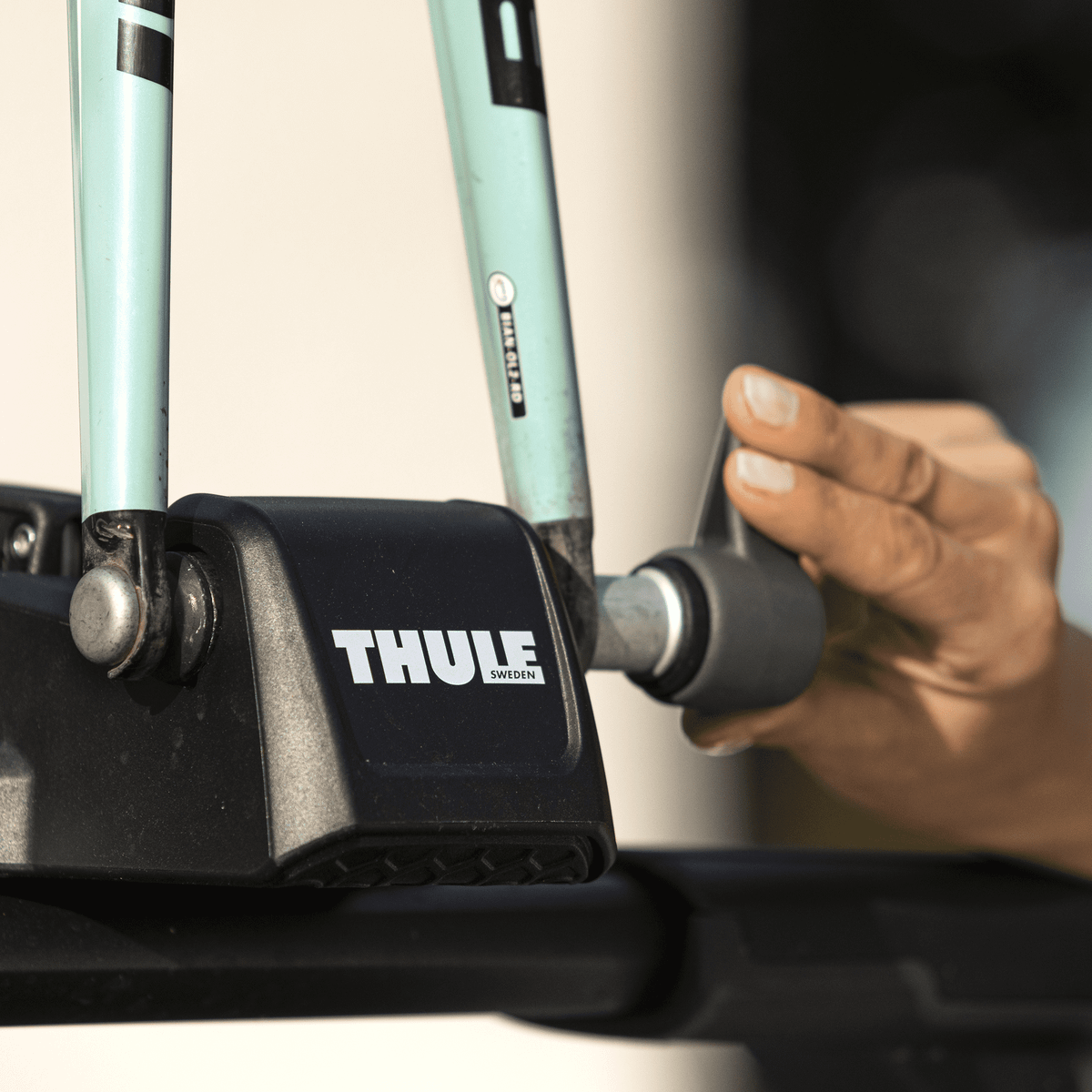 A close-up of someone loading their bikes into the Thule FastRide roof bike rack.