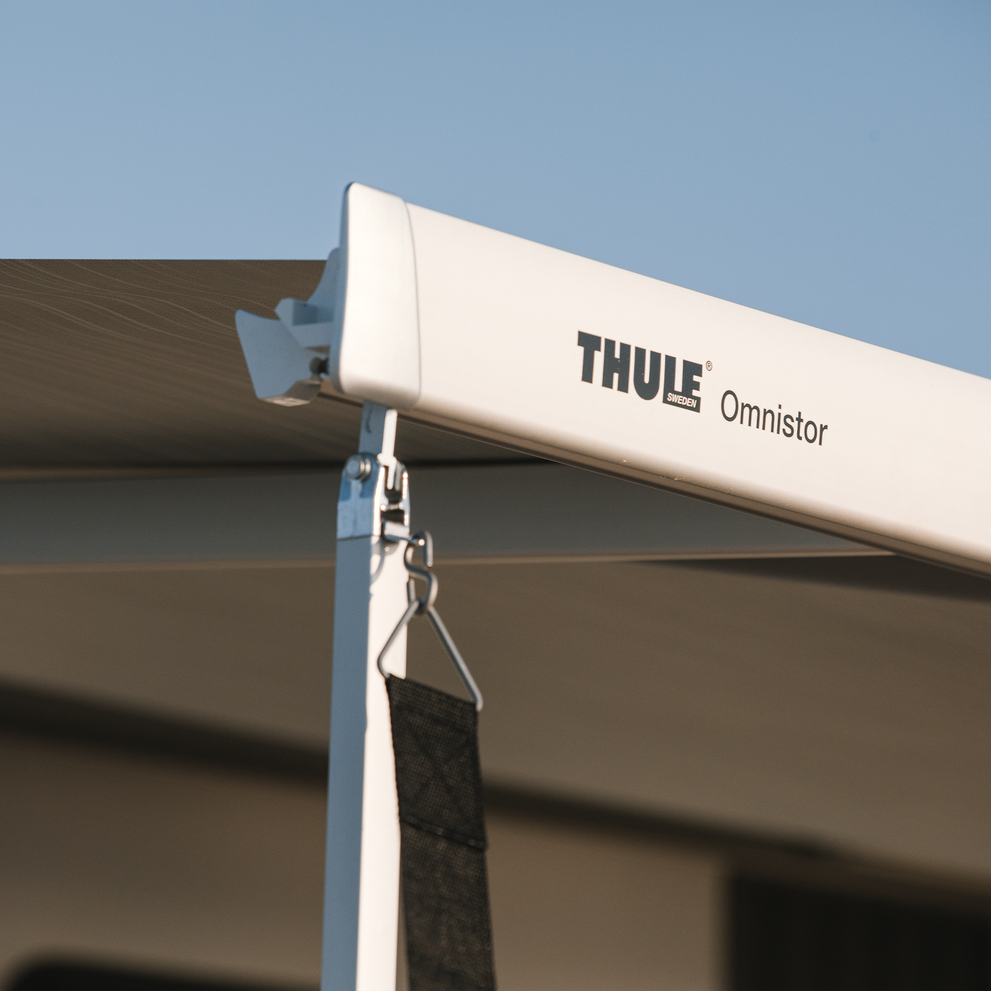 A close-up of the white awning with a Thule Hold Down Side Strap Kit.