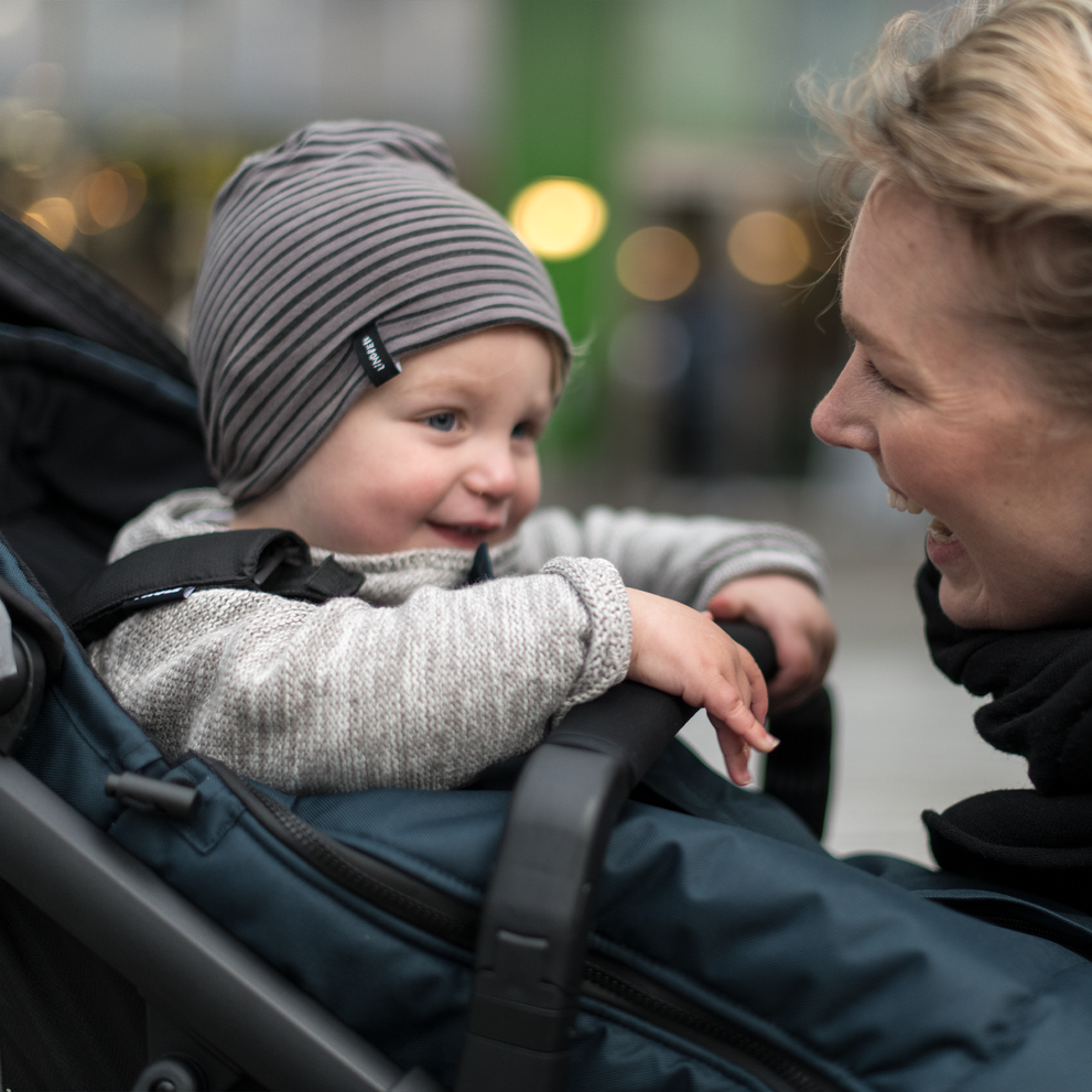 A baby smiles at his mother and holds on to the Thule Urban Glide 2 Bumper Bar.