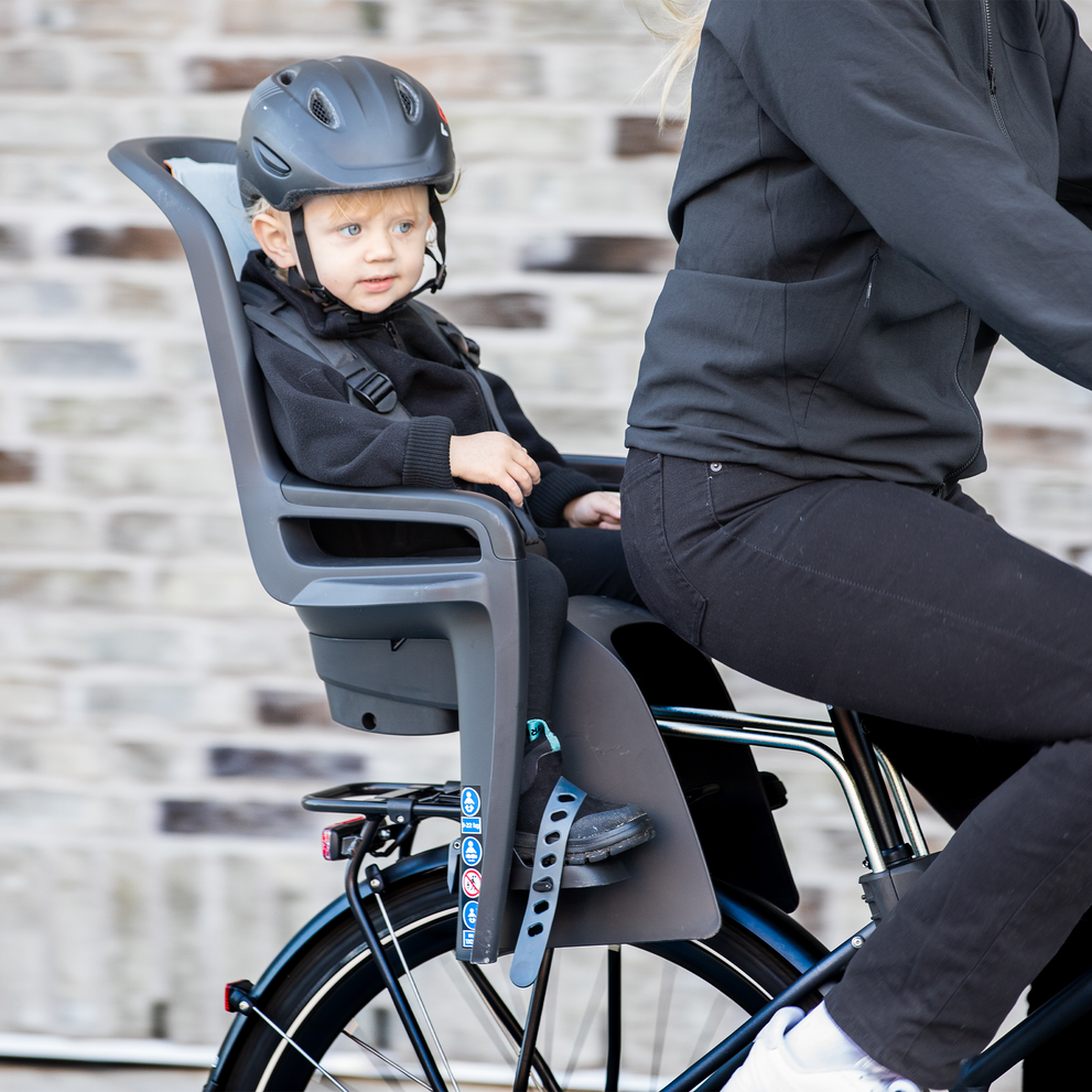 Un niño se sienta en un asiento para bicicleta Thule RideAlong2 mientras sus padres pedalean.