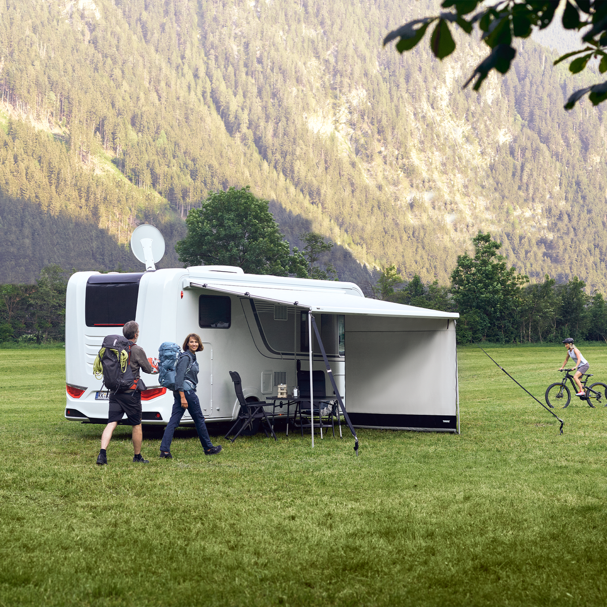 Two people hike past a white motorhome with a Thule View Blocker Side awning side wall.