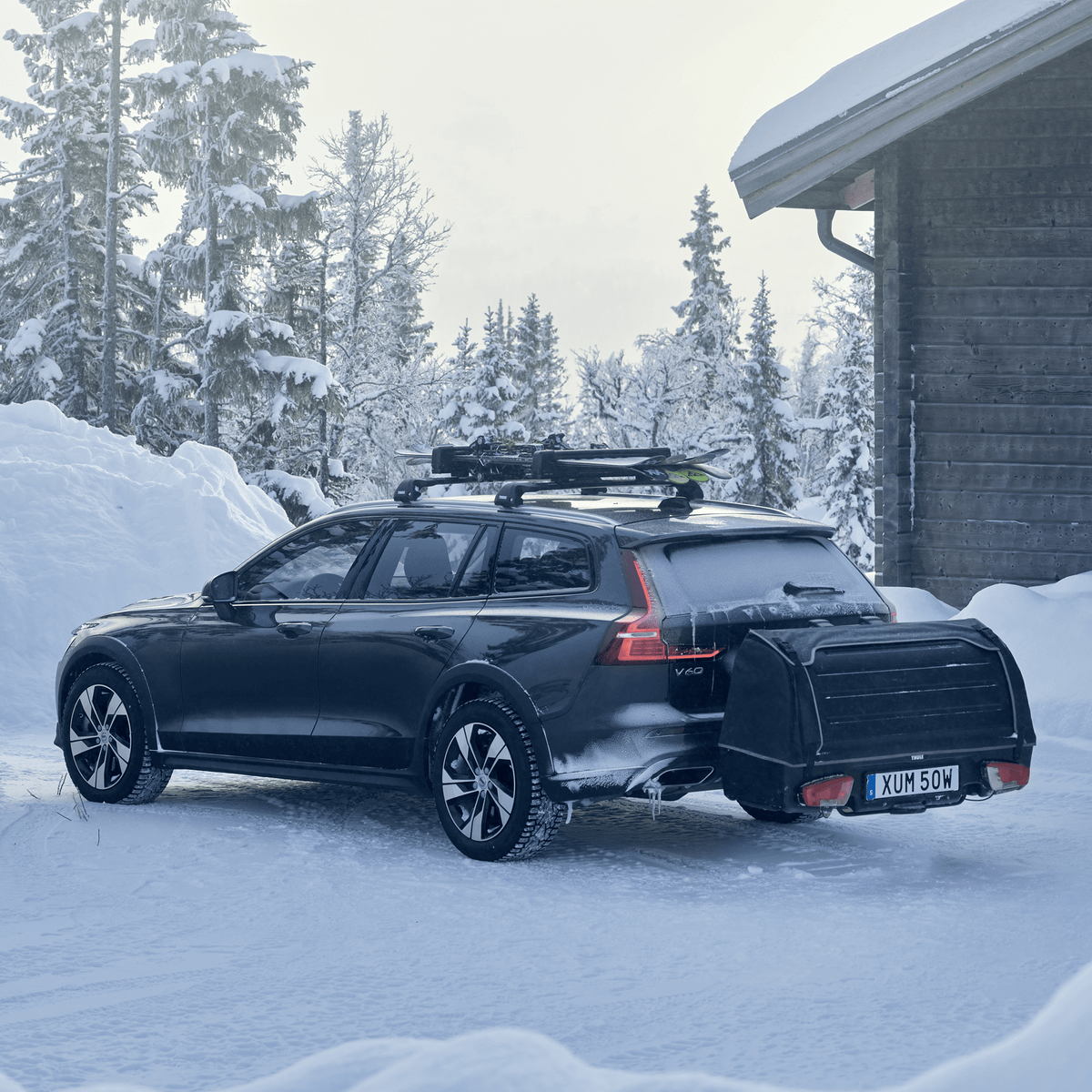 A car parked in a snowy landscape with a Thule Onto cargo box