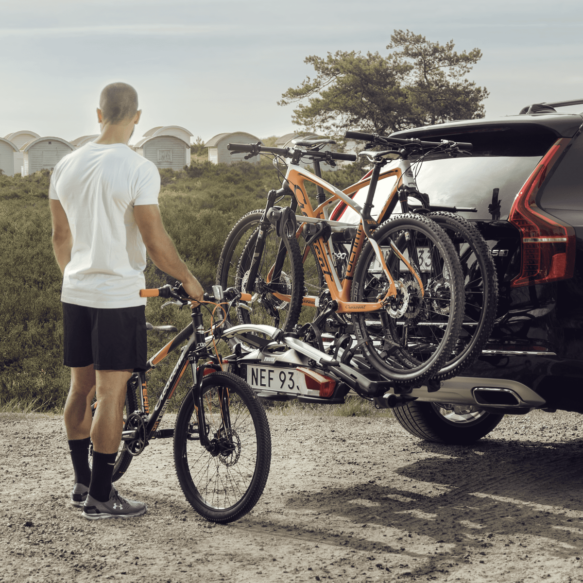 A man is loading a bike on a car with a Thule VeloCompact