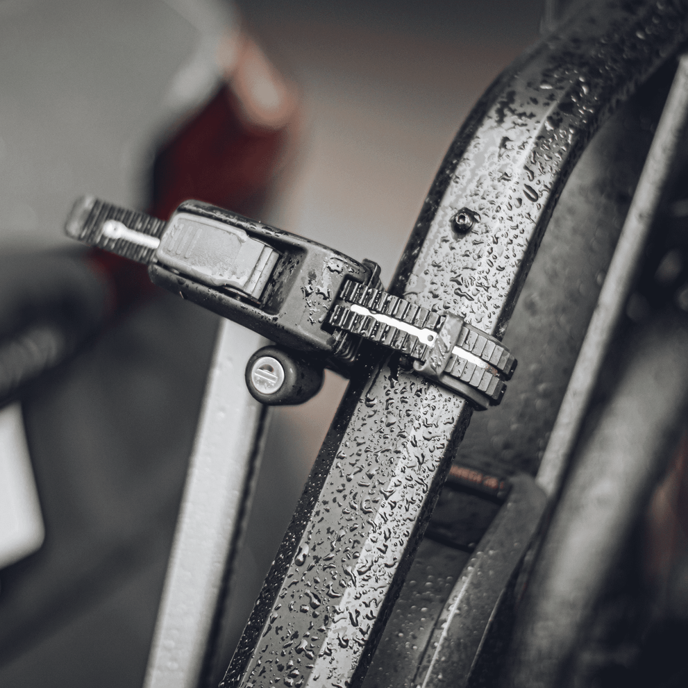 A close-up of a rain-covered ratcheting strap of the Thule Epos hitch bike rack.