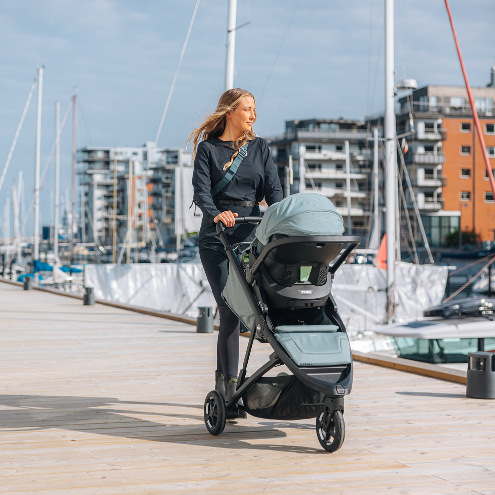 Woman pushing Thule Spring 2 with bassinet by the harbor.