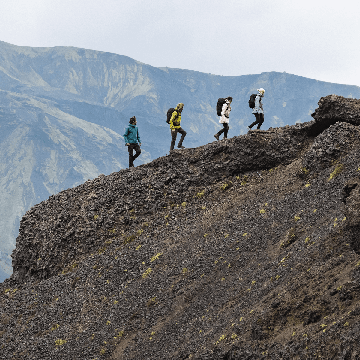 Four hikers walk up a mountain all carrying Thule Nanum 18L hiking backpacks.