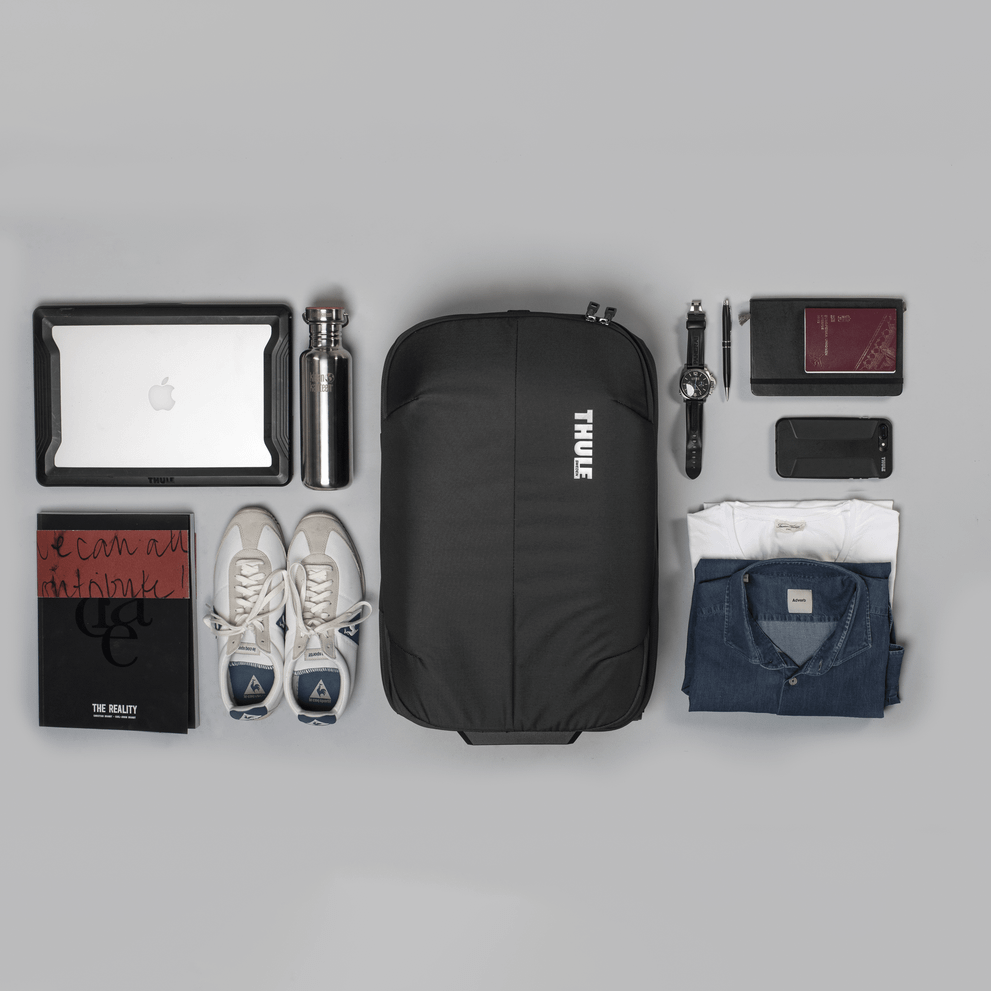 A flatlay of a Thule Subterra Carry-On suitcase with all the items spread out around it.