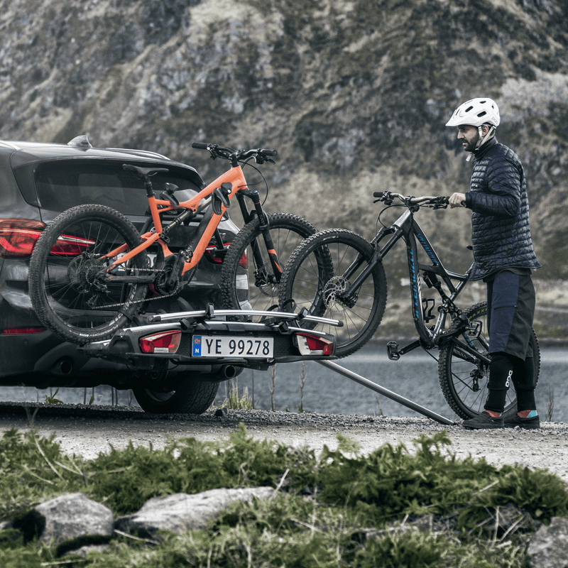 A cyclist loads their bike into a towbar bike rack with a Thule Loading Ramp XT