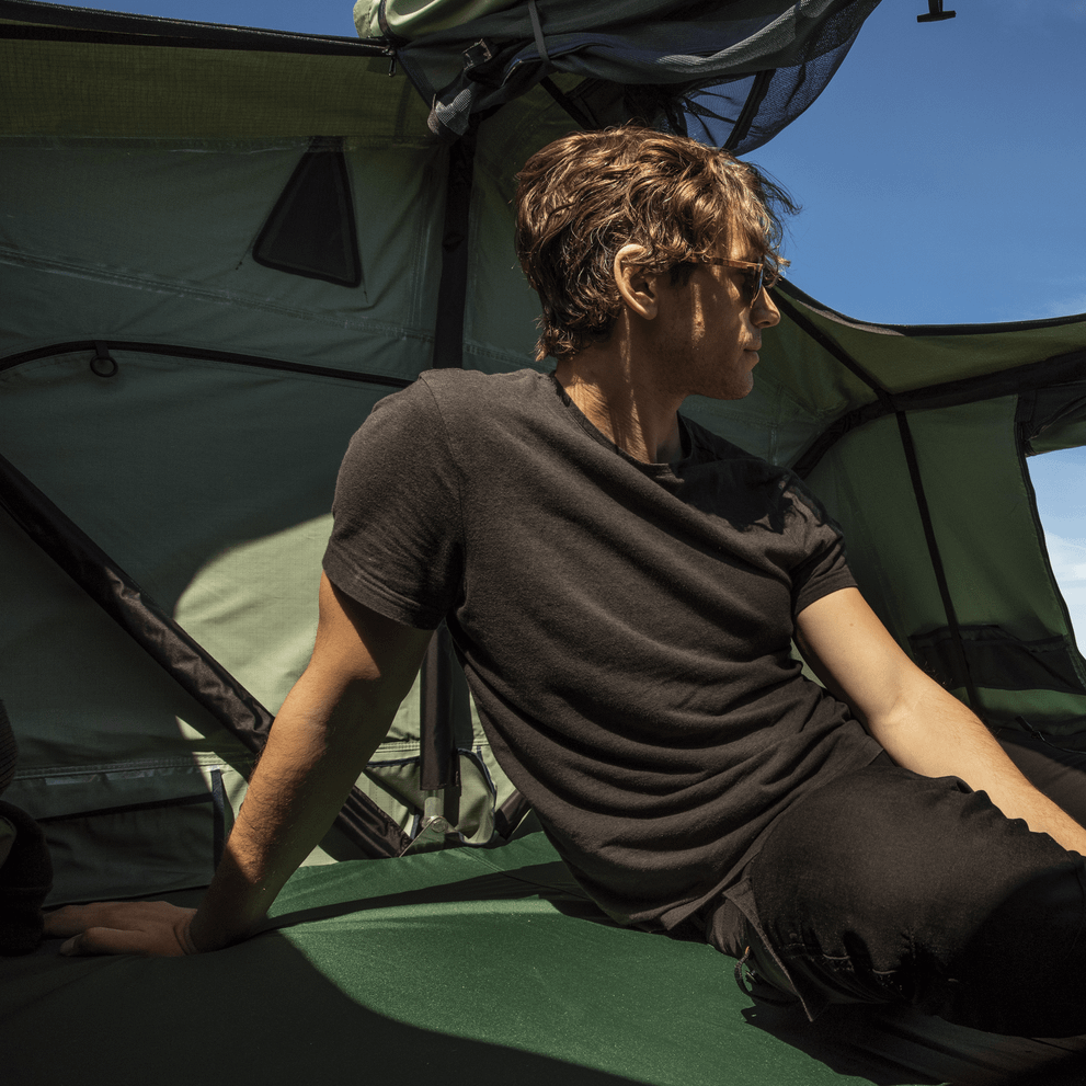 A man is looking out of the window of a Thule Tepui Kukenam rooftop tent