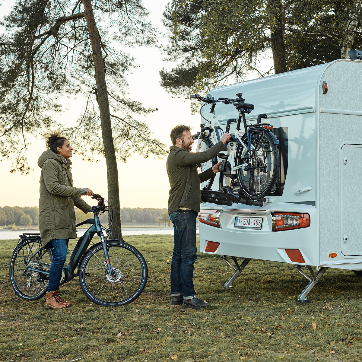 Two people unload their bikes from a Thule Excellent Standard rv bike rack.