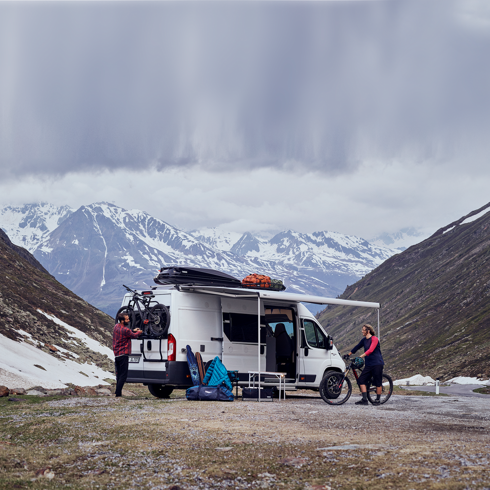 A white van parked in the mountains with a Thule Elite Van XT Black van bike rack.