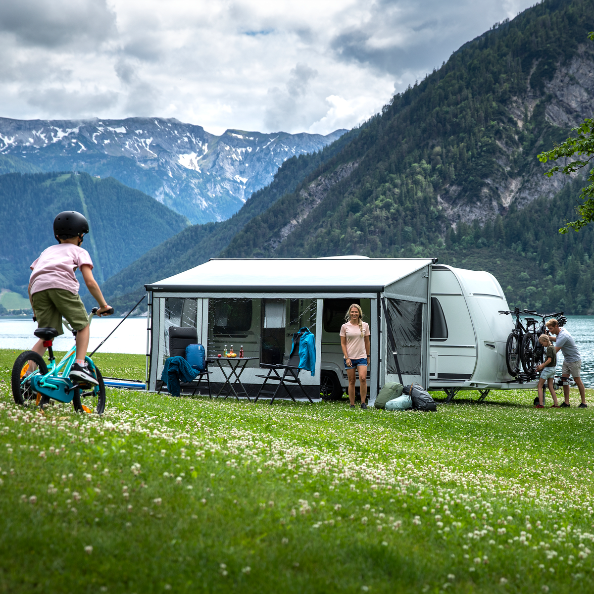 A motorhome parked next to the water parked in the mountains with a Thule Residence G3 rv awning tent.