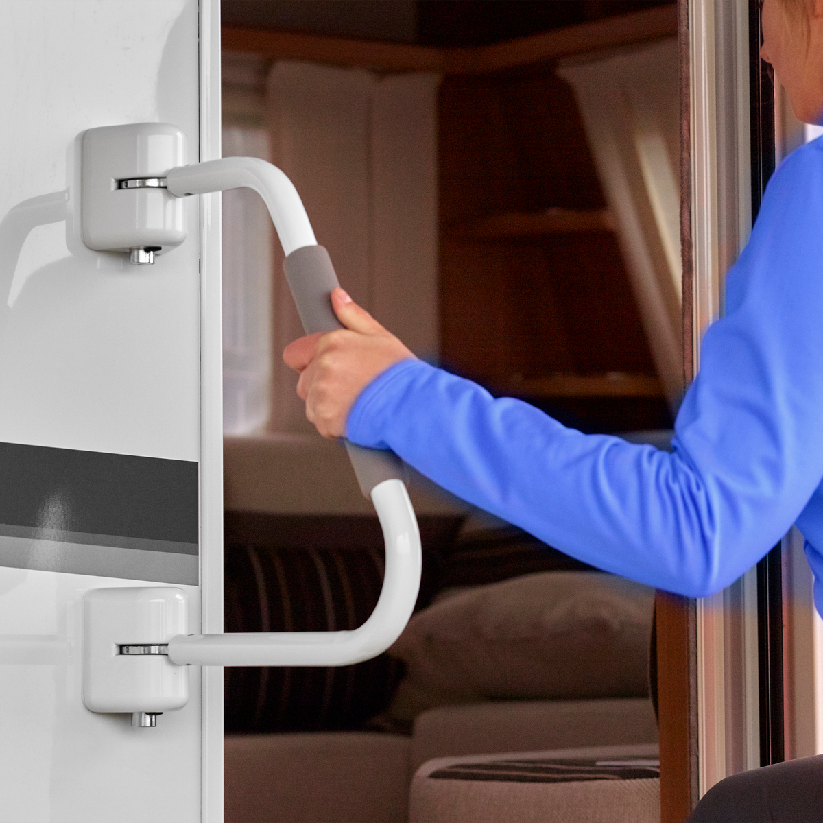 A person holding a Thule Security Handrail to enter their caravan.