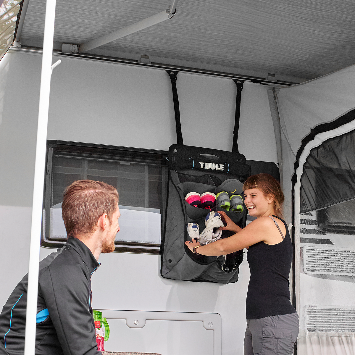 A woman loads items into an rv organizer attached with a Thule Strap kit for Organizers.
