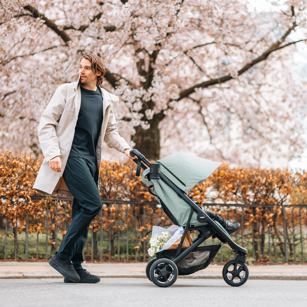 Woman walking with Thule Spring 2 under cherry blossoms.