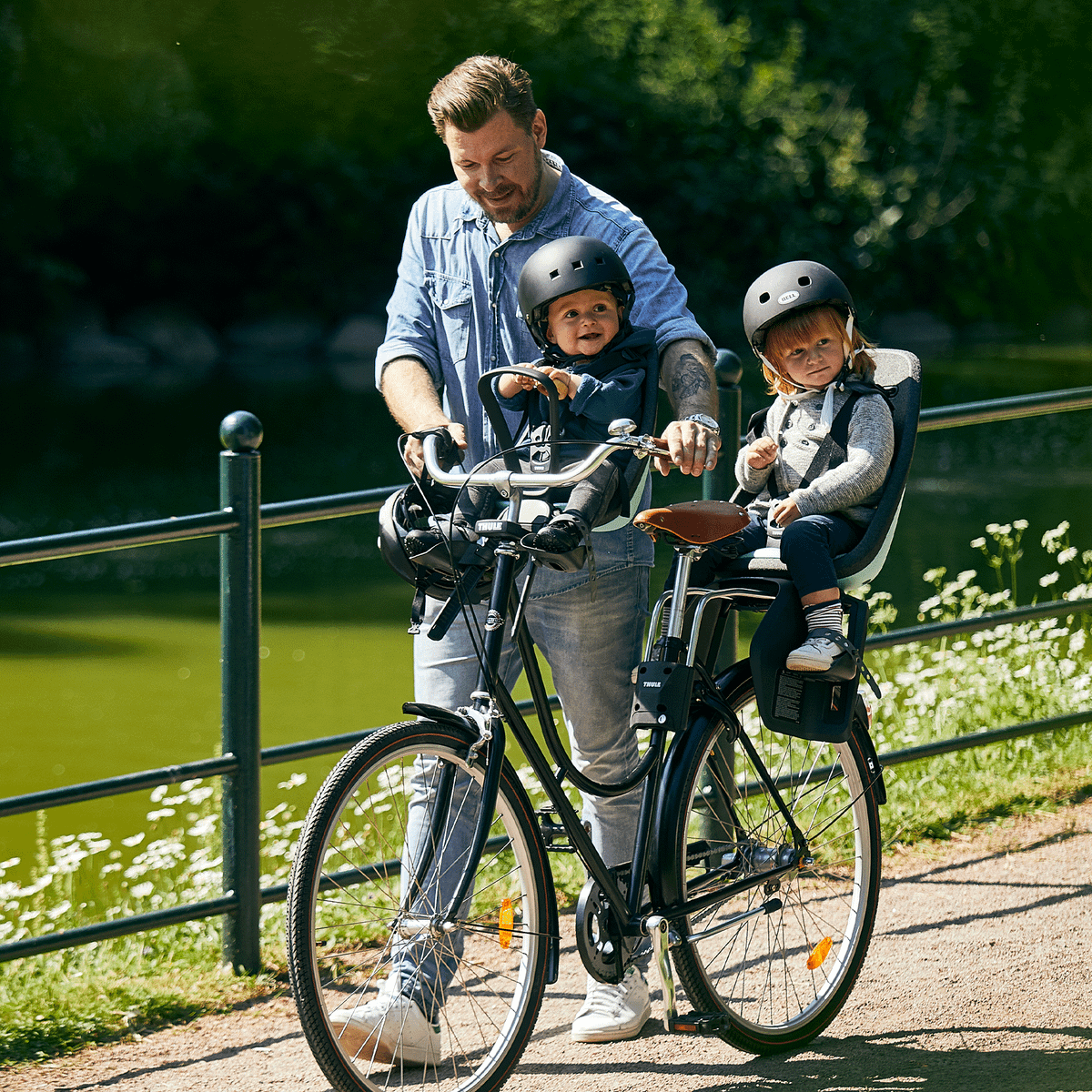 A man pulls his kids sitting in e Thule Yepp Nexxt Mini child bike seat.