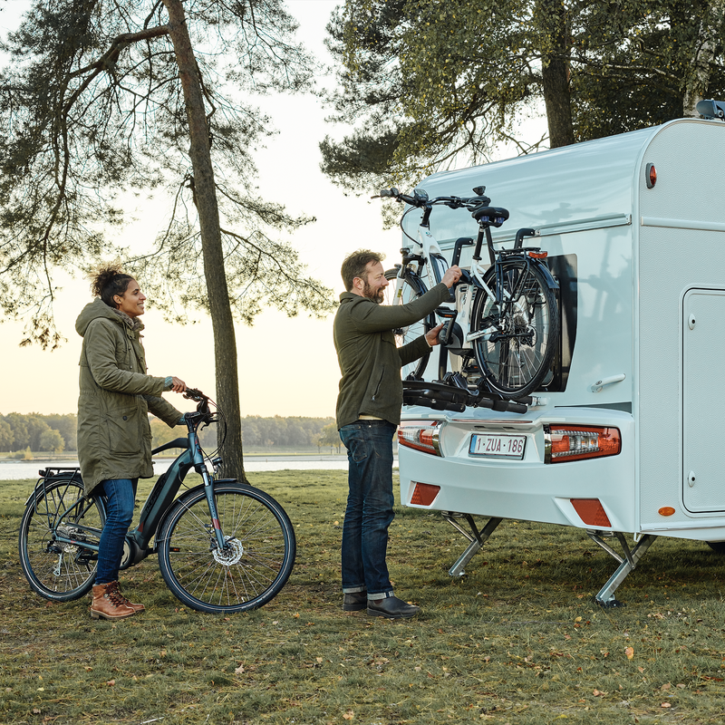 Two people unload their bikes from a Thule Excellent Standard rv bike rack.