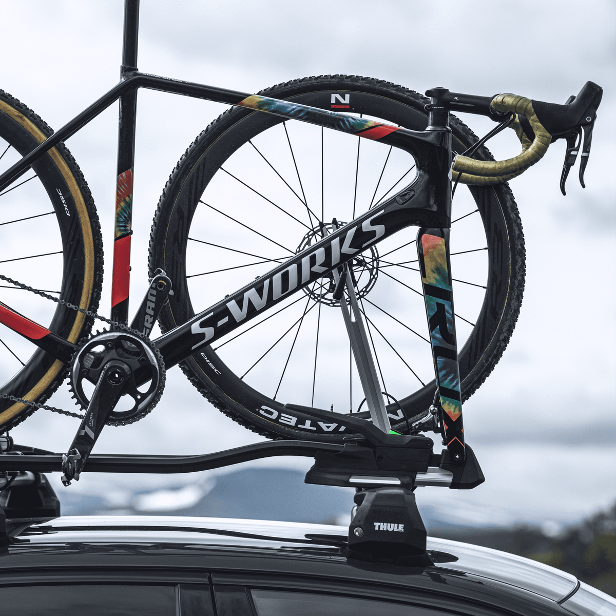 A road bike is mounted to a car with a Thule TopRide bike carrier