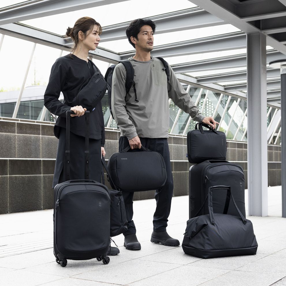 A man and woman walk down a street holding all the Thule Subterra luggage.