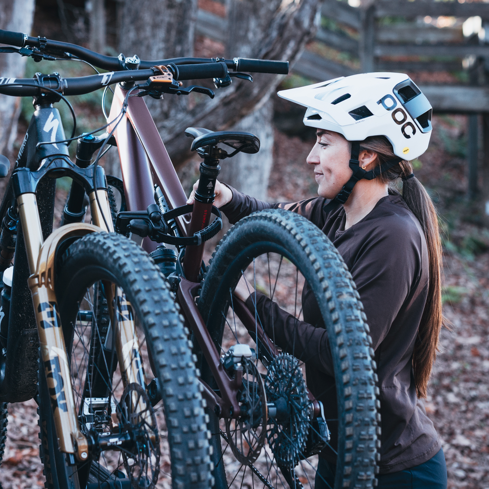 A woman is securing a bike with the pivoting arms on the Thule Vero hitch bike rack.