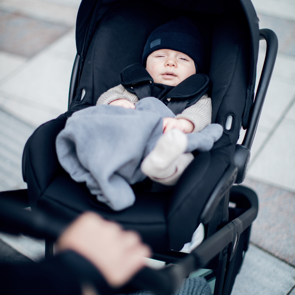 A baby sleeps bundled in a car seat thanks to the Thule Shine Car Seat Adapter.