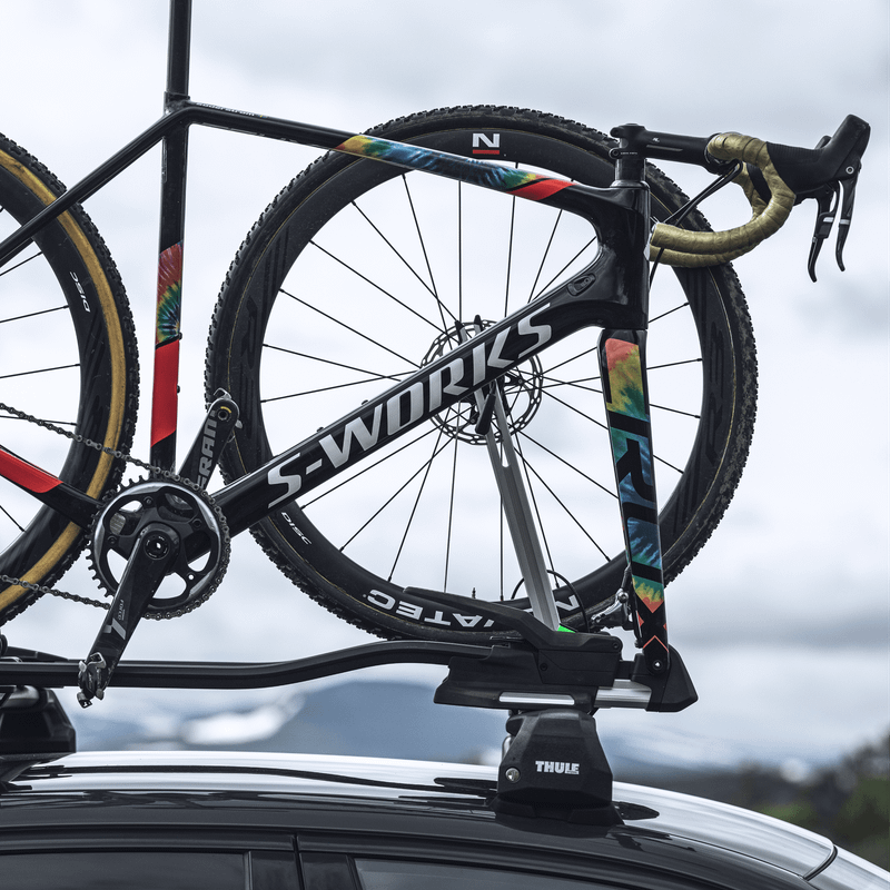 A road bike is mounted to a car with a Thule TopRide bike carrier