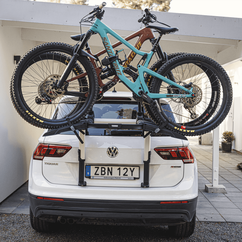 A car is parked in the drive way with bikes installed on the Thule Outway 2bike Platform trunk bike rack.