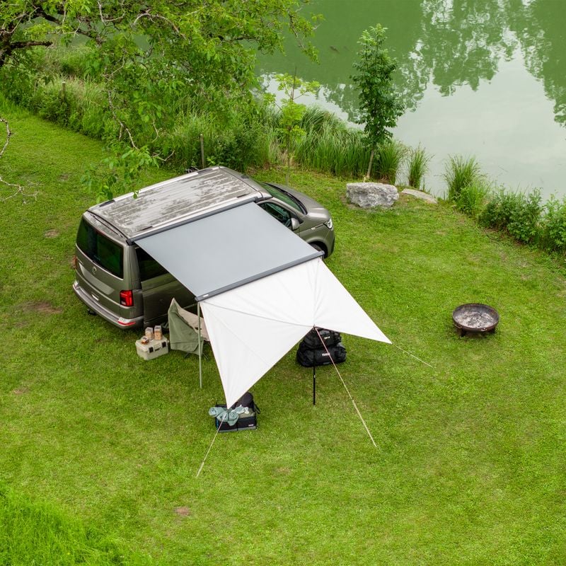 A van is parked next to the water with the Thule Subsola versatile awning panels.