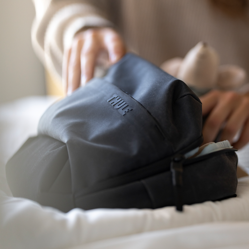 Close-up of hands packing items into a Thule Aion changing bag.