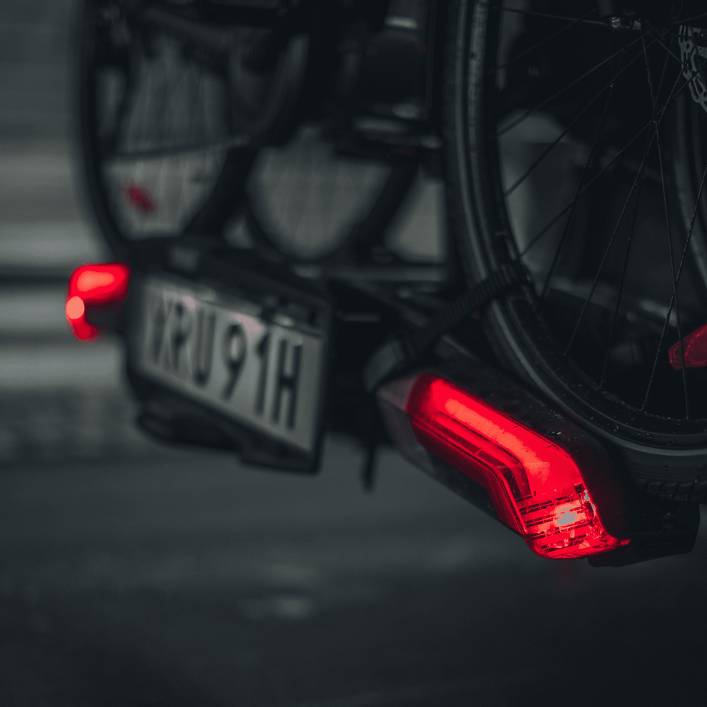A close-up of the rear lights of the Thule Epos hitch bike rack in the dark.