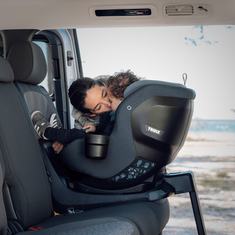 Adult attaching a Thule Maple Connect infant car seat to the Thule Alfi Connect ISOFIX base in the back seat of a vehicle.