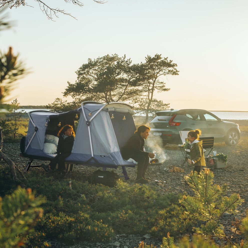 A woman and her two kids are camping in a Thule Outset tent.