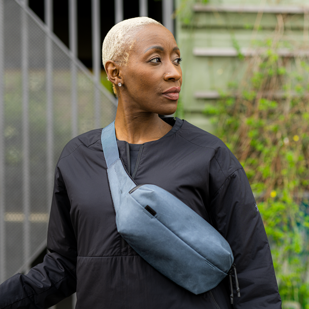 Zwei Personen gehen einen Strand entlang, der Mann trägt eine Sporttasche und die Frau eine Thule Aion Sling Bag.