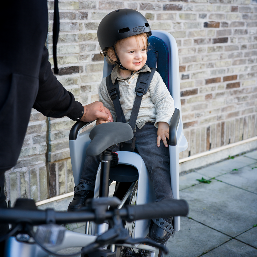 A close up of a child with a black helmet sitting in a Thule RideAlong2 child bike seat.