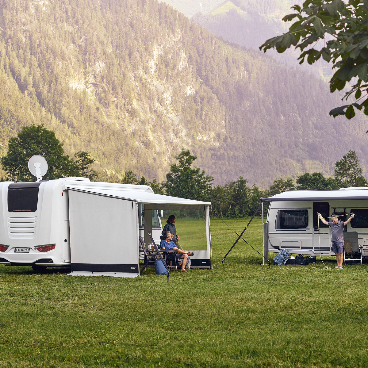 Two white motorhomes are parked next to the mountain with a Thule View Blocker Side awning side wall.