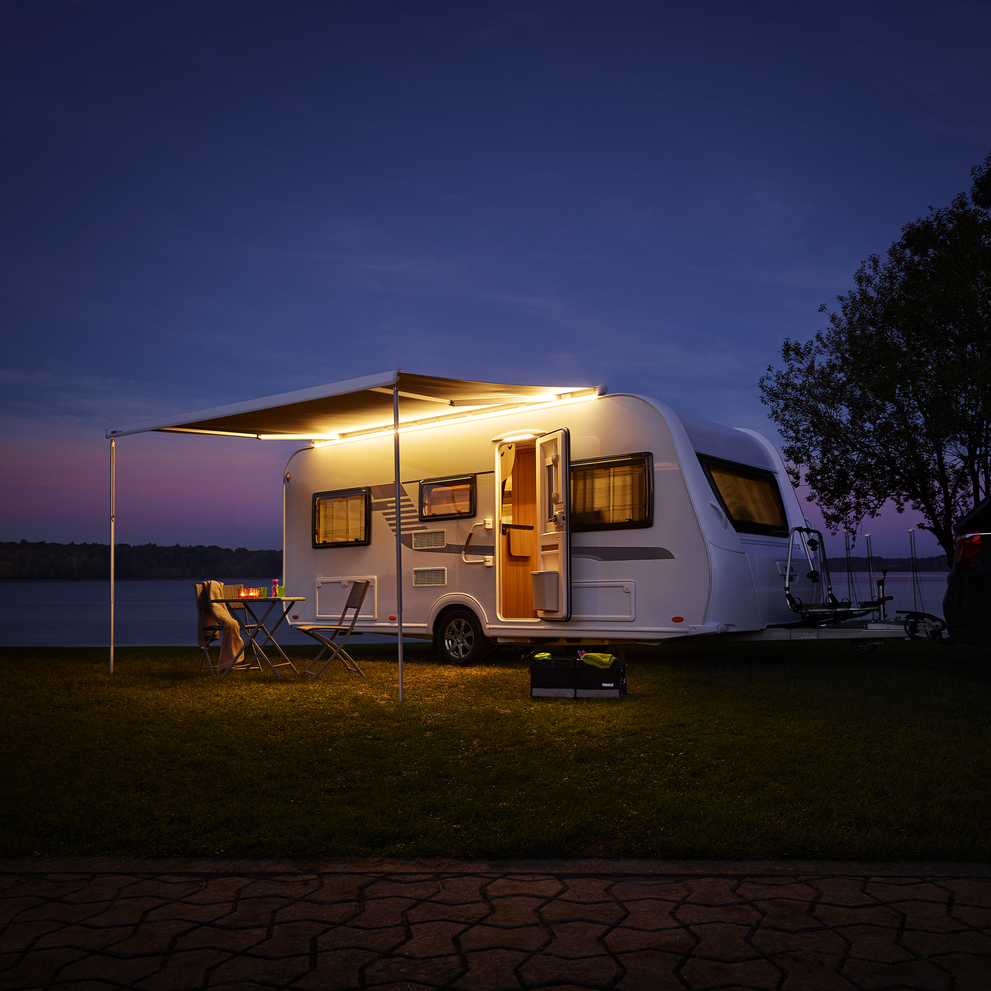 A caravan at night with lights and a Thule Tent LED Mounting Rail and RV lights.
