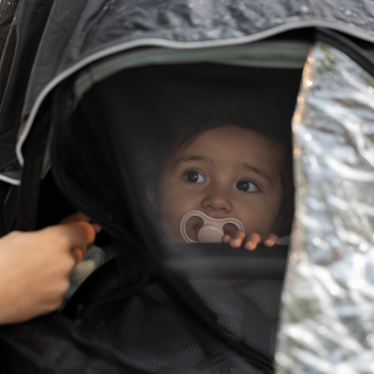 A close-up of a baby inside a black Thule Shine stroller with a Thule Shine All-weather Cover.