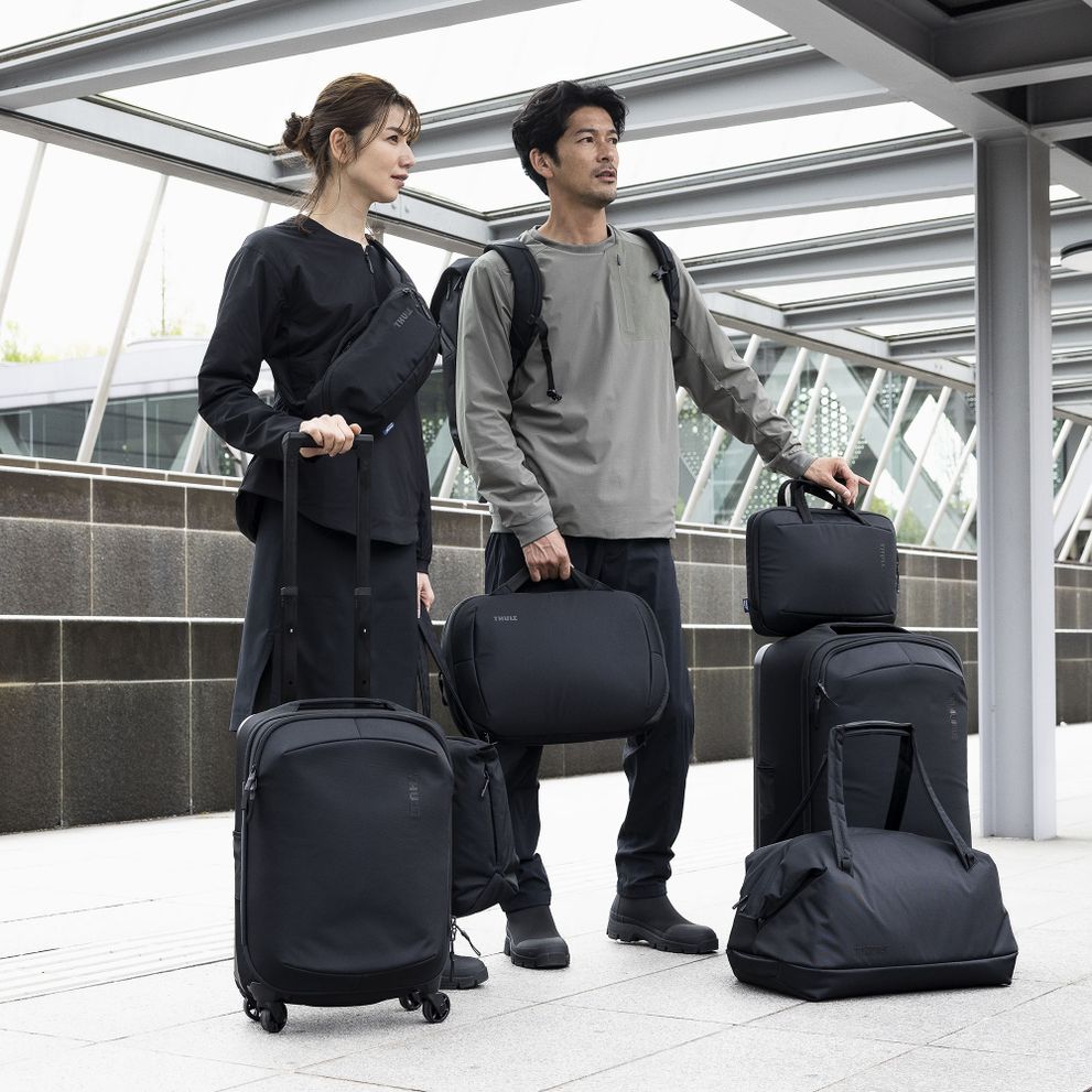 A man and a woman stand on a train platform with Thule Subterra luggage bags.